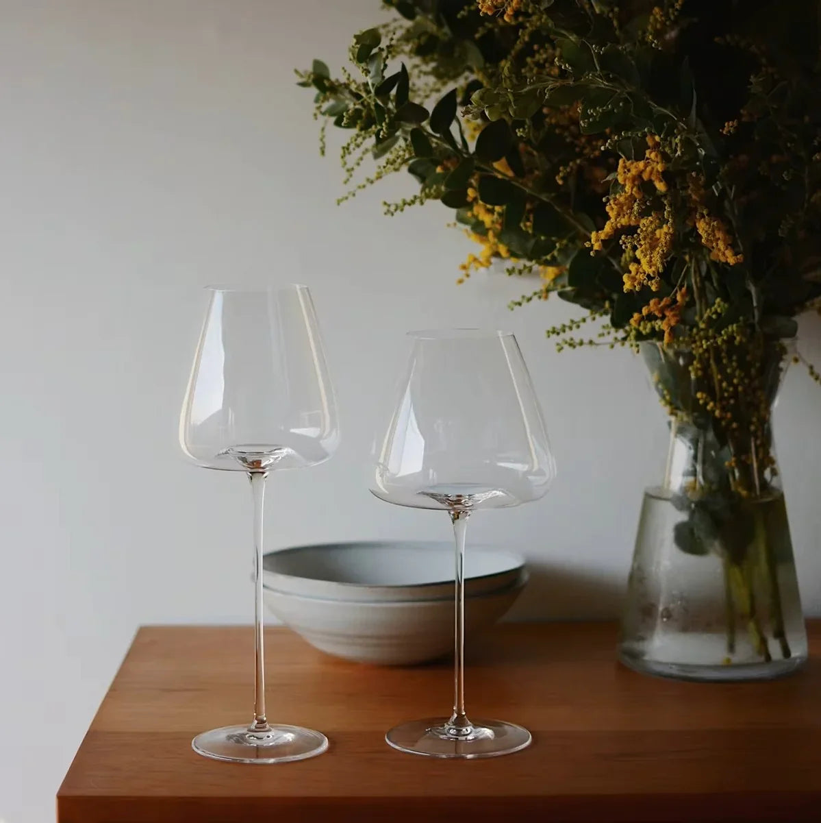 Zwei hochwertige Weingläser auf Holztisch, elegantes Küchendekor mit Vase und Schale