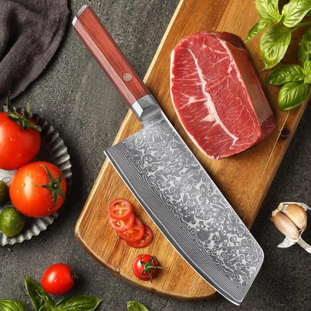 Edles Küchenmesser mit Damastmuster auf Holzbrett, frisches Fleisch, Tomaten, Kräuter und Knoblauch