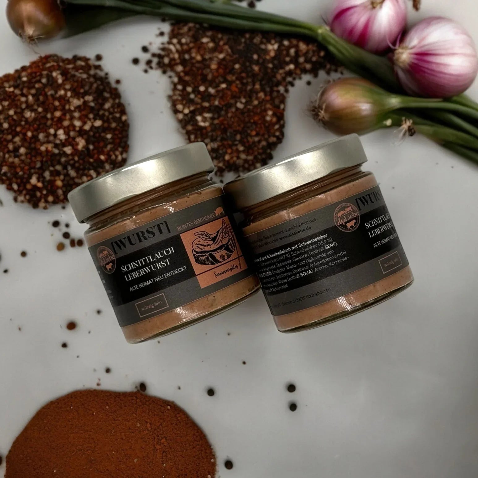 Zwei Gläser Schnittlauch-Leberwurst auf weißer Arbeitsplatte, mit Gewürzen, Frühlingszwiebeln und Schalotten – exklusive Küchenutensilien und Accessoires für stilvolles Kocherlebnis.
