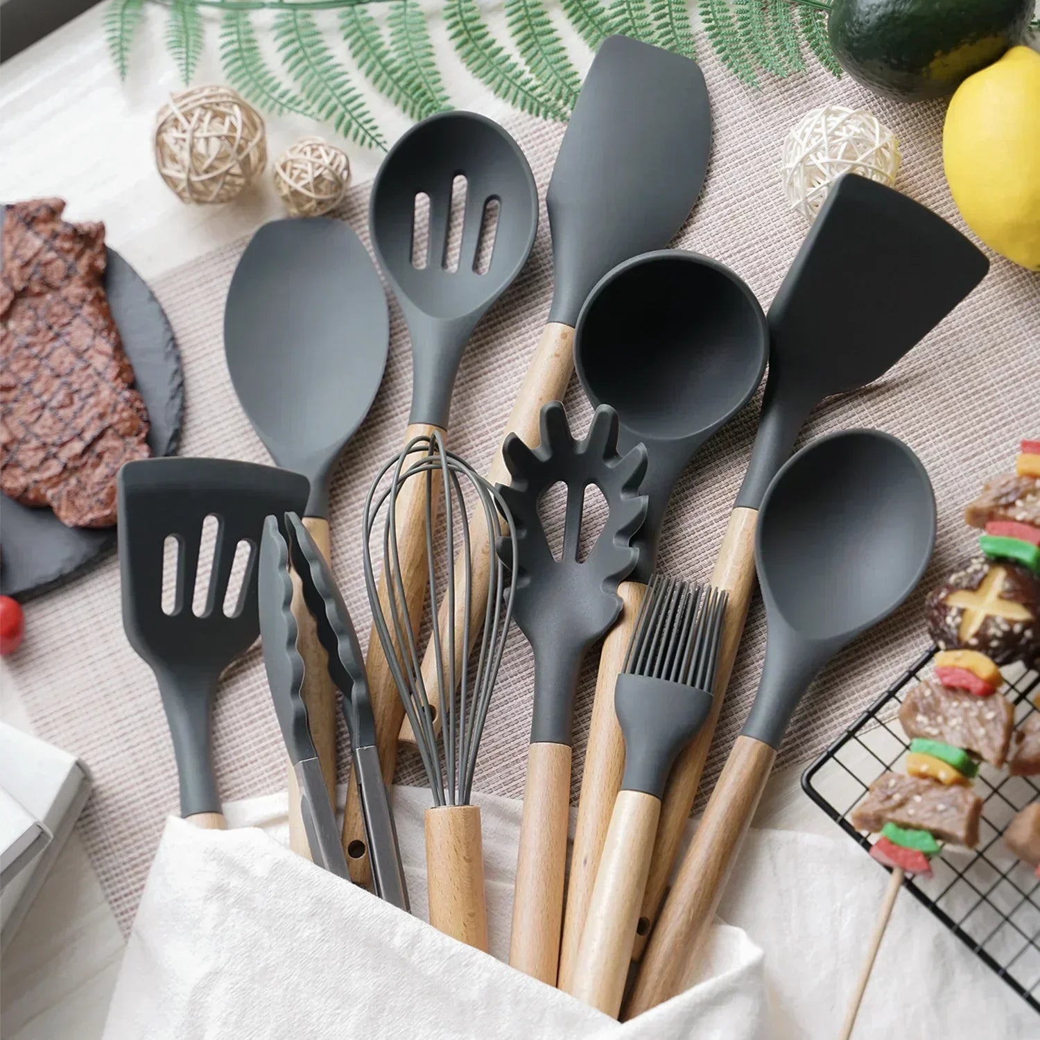12-teiliges Silikon-Küchenutensilien-Set mit Holzgriffen, modern auf Küchentisch arrangiert.