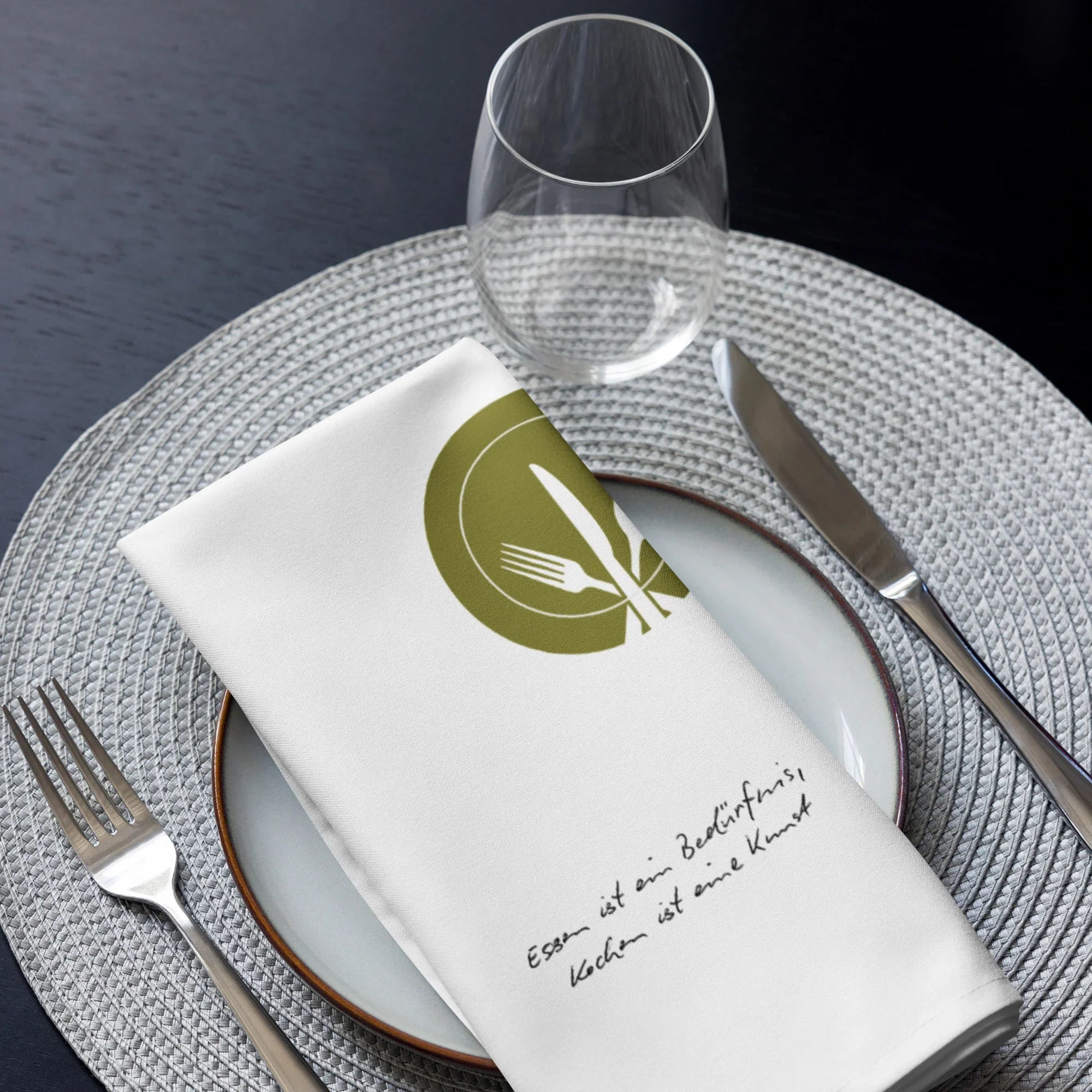 Elegantes weißes Stoffservietten-Set mit Besteck-Motiv und Schriftzug auf gedecktem Tisch, exklusiv bei Kochschein.
